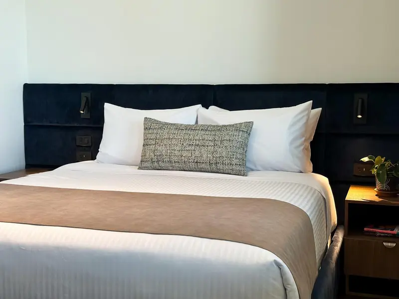 Un lit double avec des oreillers blancs et un couvre-lit marron dans une chambre.