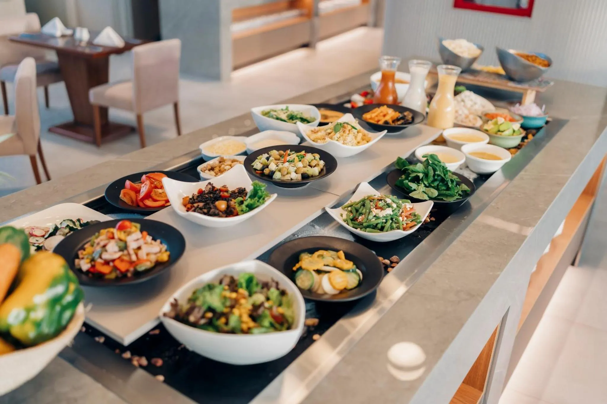 Un buffet propose une variété de salades et de plats préparés sur une longue table.