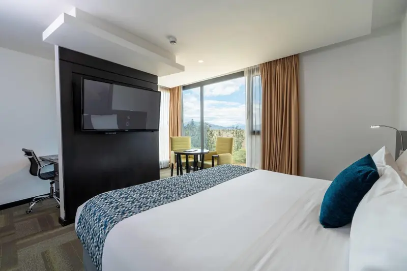 Chambre lumineuse avec un grand lit et une vue sur le paysage.