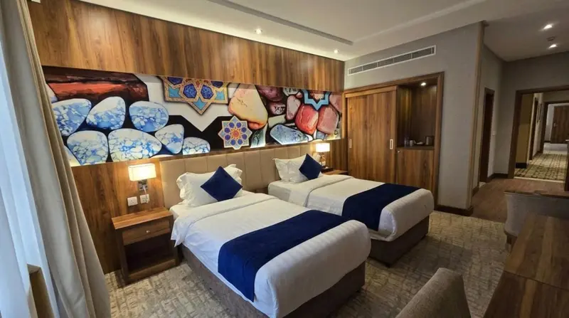 Une chambre d'hôtel moderne avec deux lits simples et une décoration murale colorée.