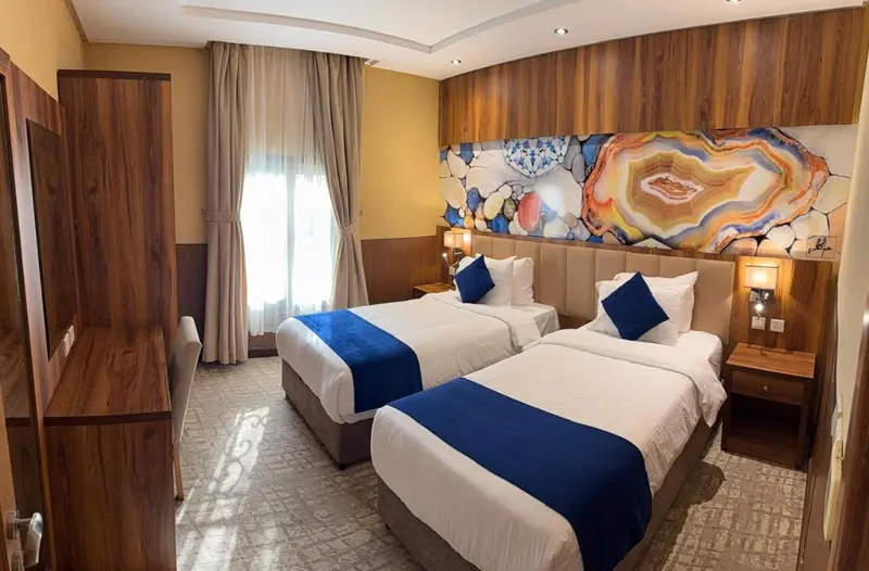 Chambre avec deux lits simples et décoration murale.