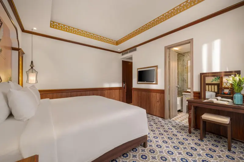 Une chambre lumineuse avec un grand lit et un bureau en bois.
