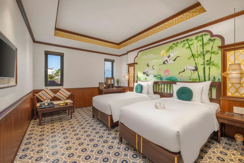 Chambre lumineuse avec deux lits simples et décoration florale.