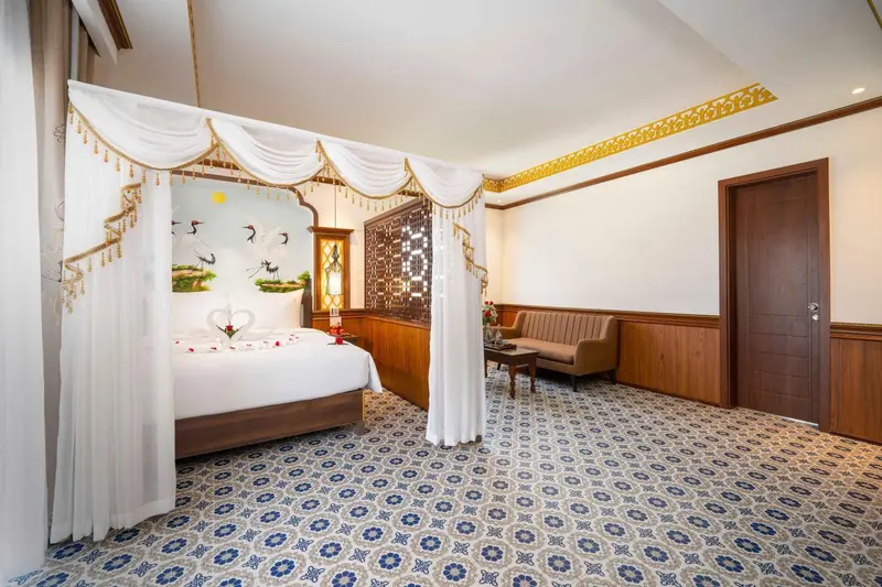 Chambre avec un grand lit à baldaquin et un canapé.