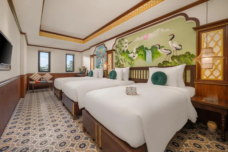 Chambre lumineuse avec deux lits simples et une décoration murale florale.