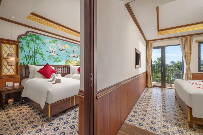 Chambre lumineuse avec lits décorés de fleurs et vue sur la végétation.