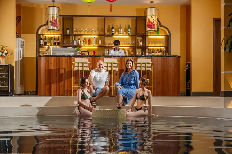 Un bar avec des clients assis et debout près d'une piscine intérieure.
