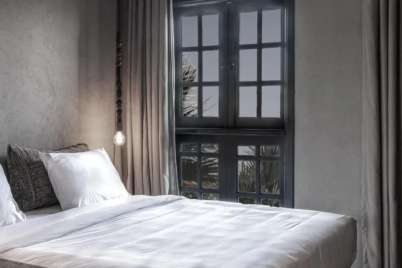 Une chambre lumineuse avec un lit fait et une fenêtre à carreaux.