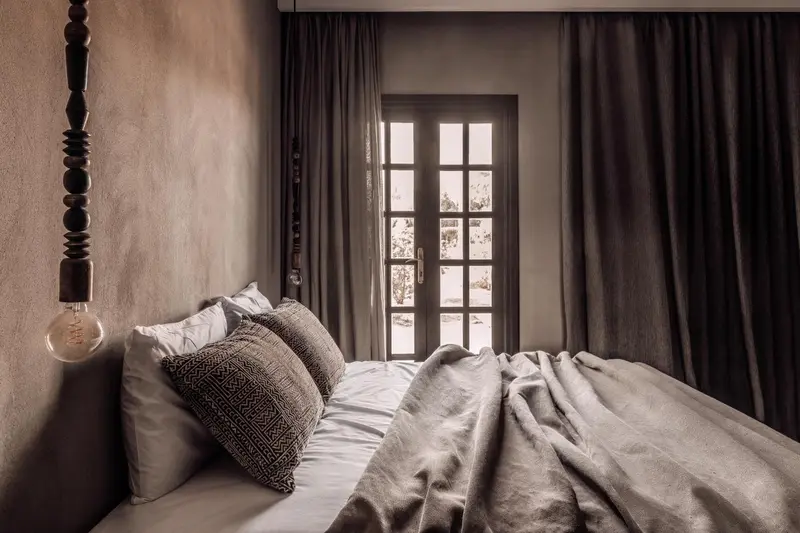 Une chambre à coucher avec un lit fait et une fenêtre ouverte sur l'extérieur.
