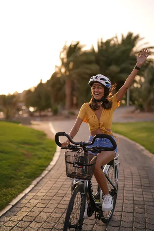 Une femme souriante fait du vélo sur une allée pavée.