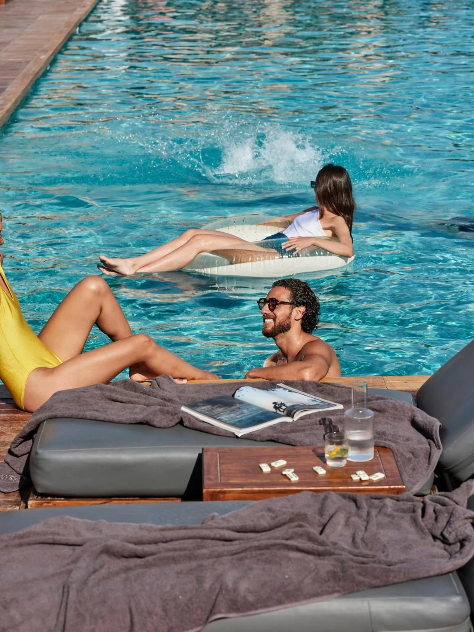 Des personnes se détendent au bord d'une piscine ensoleillée.