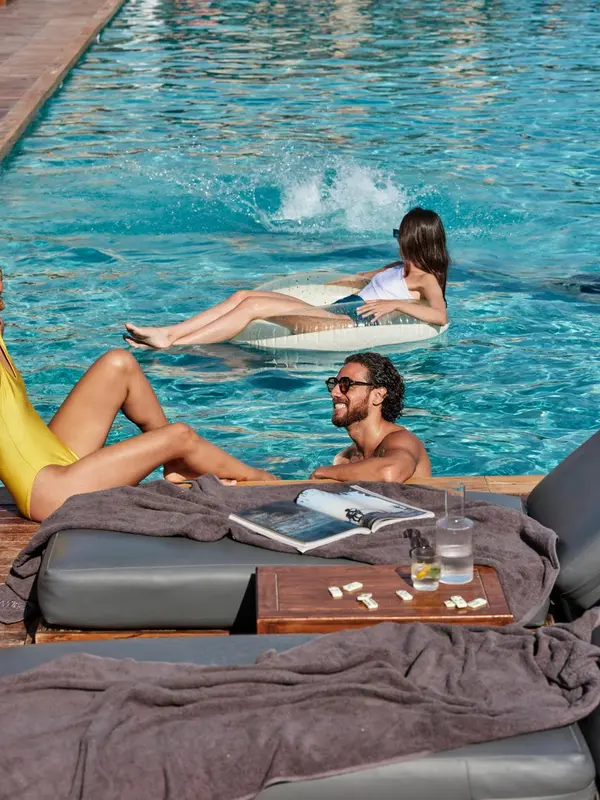 Des personnes se détendent au bord d'une piscine ensoleillée.