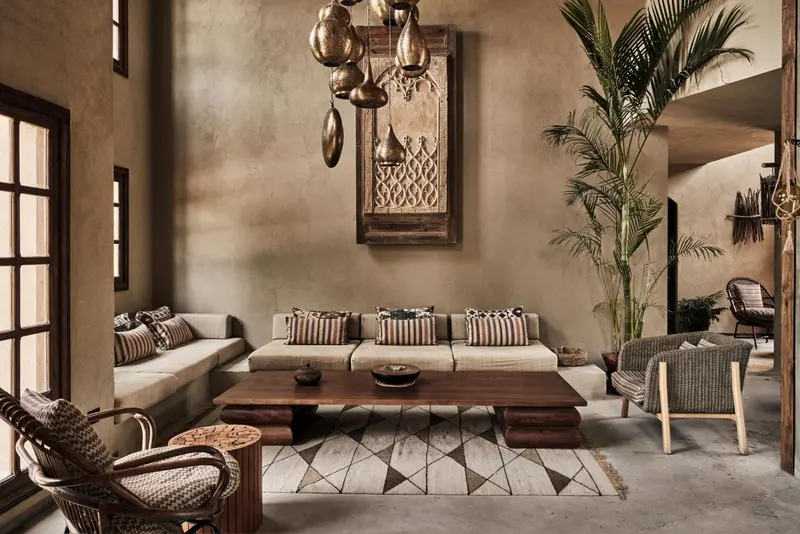 Un espace de détente intérieur avec canapés, table basse et fauteuils en rotin.
