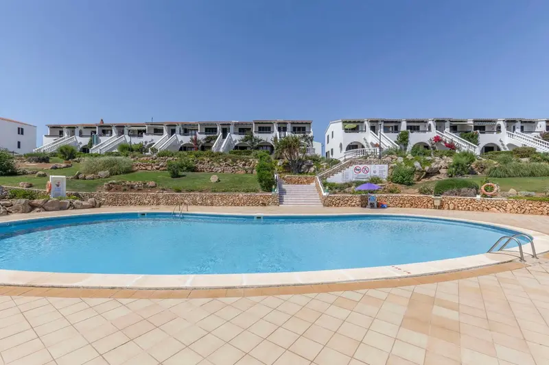 Piscine rectangulaire devant un bâtiment blanc à plusieurs niveaux.