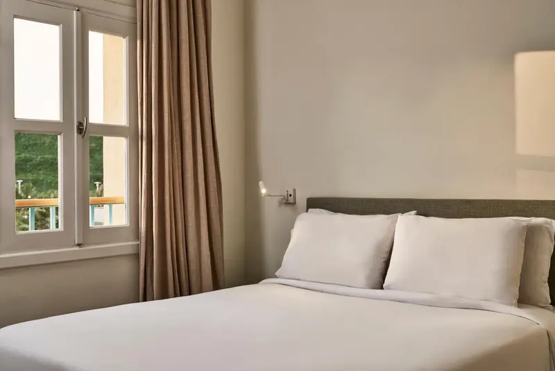 Une chambre lumineuse avec un lit fait et une fenêtre ouverte.