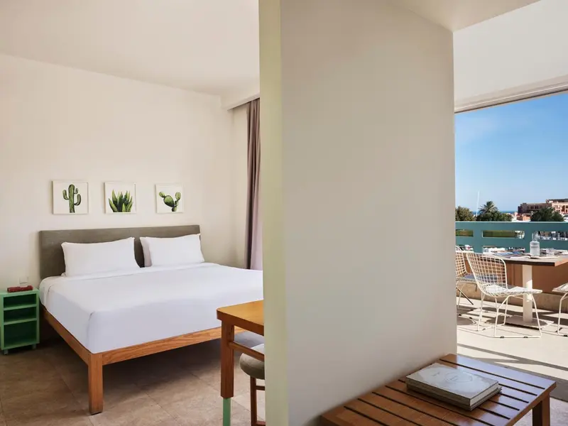 Une chambre lumineuse avec un lit double et une terrasse ensoleillée.