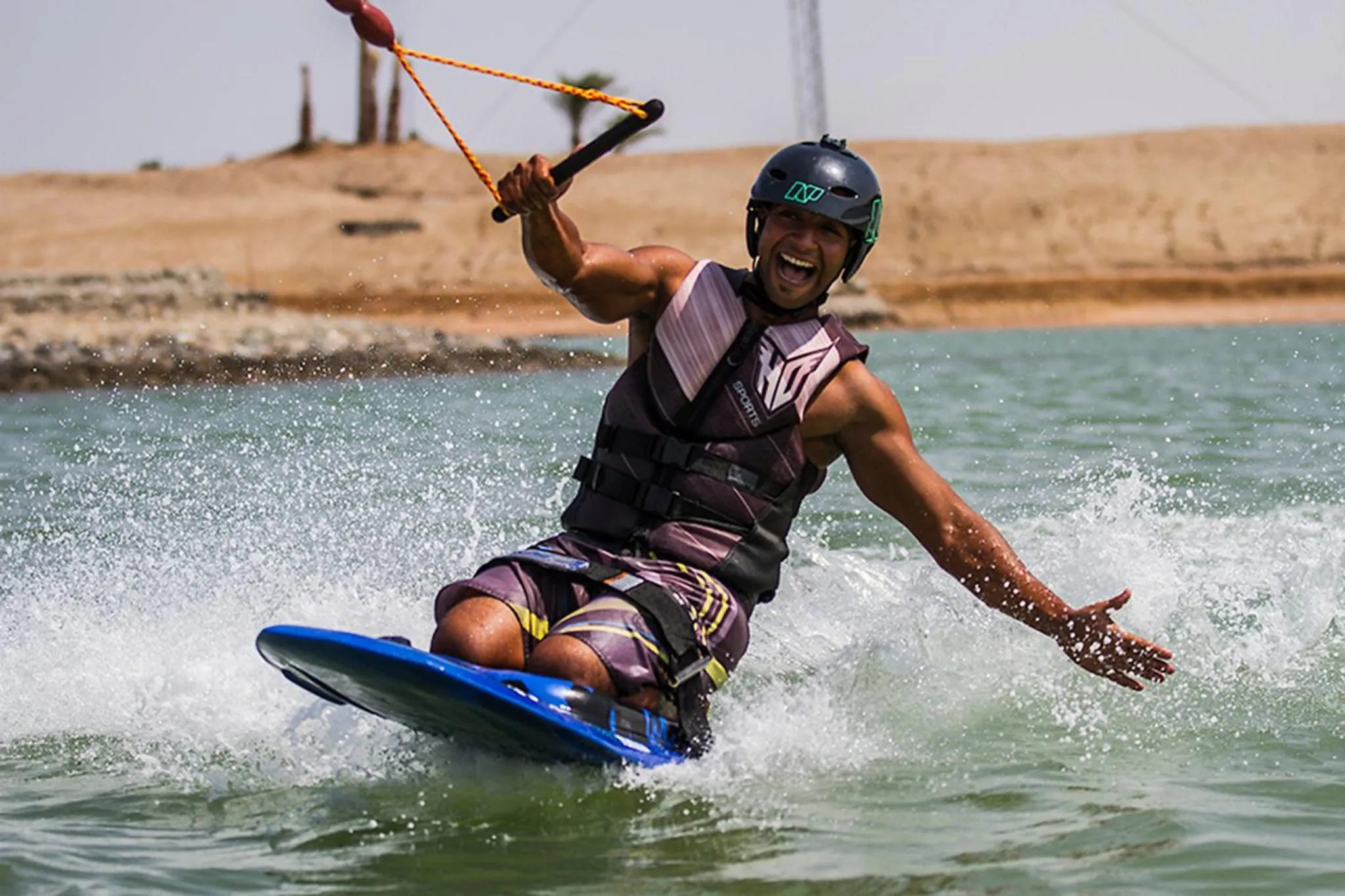 Un homme pratique le wakeboard sur une étendue d'eau turquoise.