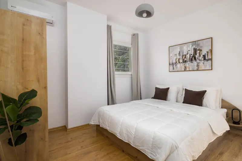 Une chambre lumineuse avec un grand lit recouvert d'une couette blanche et de coussins.
