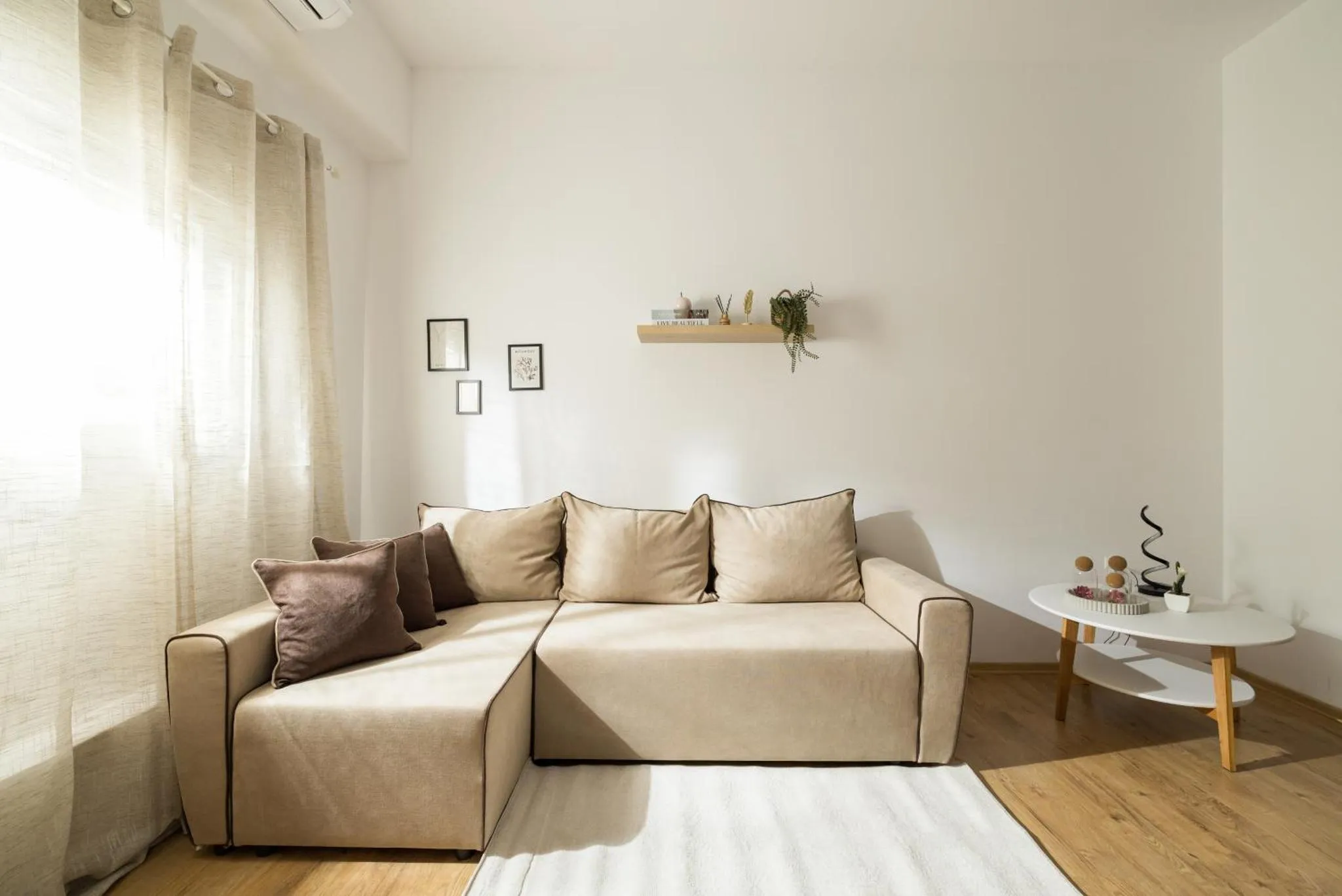 Un canapé beige est installé dans un intérieur clair et minimaliste.