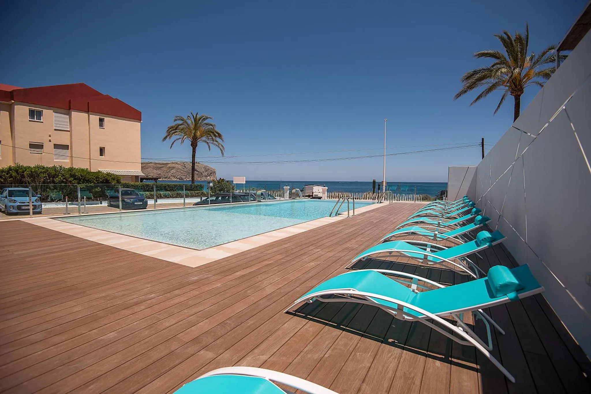 Terrasse avec transats et piscine au bord de la mer.