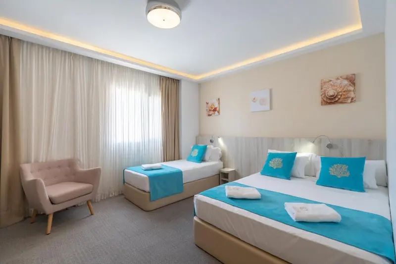 Une chambre lumineuse avec deux lits simples et un fauteuil.