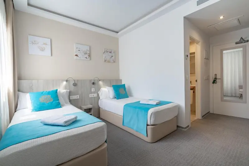 Une chambre lumineuse avec deux lits simples et une décoration sobre.