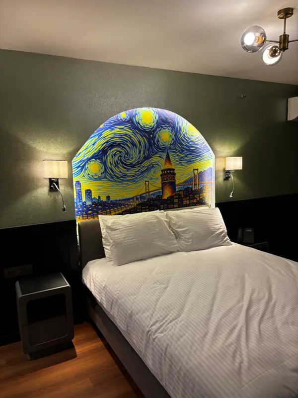 Une chambre avec un lit recouvert d'une couette blanche et une décoration murale représentant un paysage urbain.