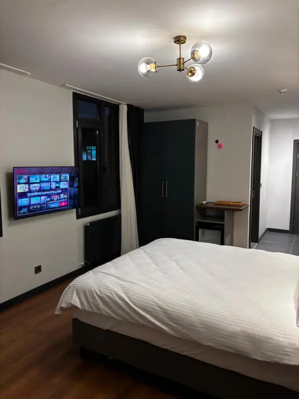 Une chambre lumineuse avec un grand lit et un téléviseur mural.