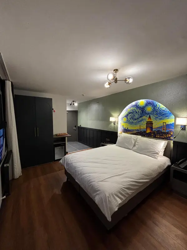 Une chambre lumineuse avec un grand lit blanc et une décoration murale originale.