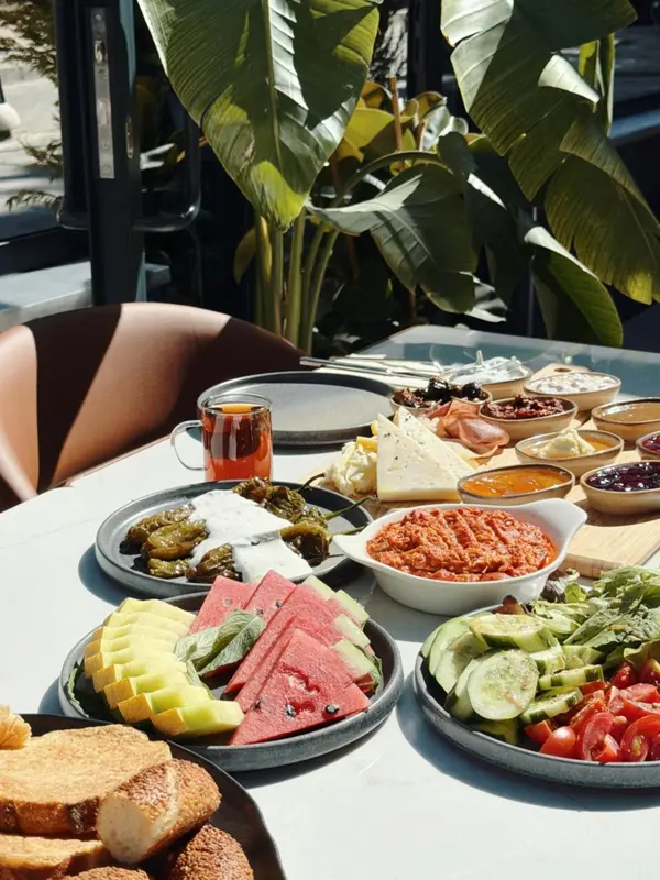 Une table est dressée avec un copieux petit-déjeuner composé de fruits, de fromages et d'accompagnements.