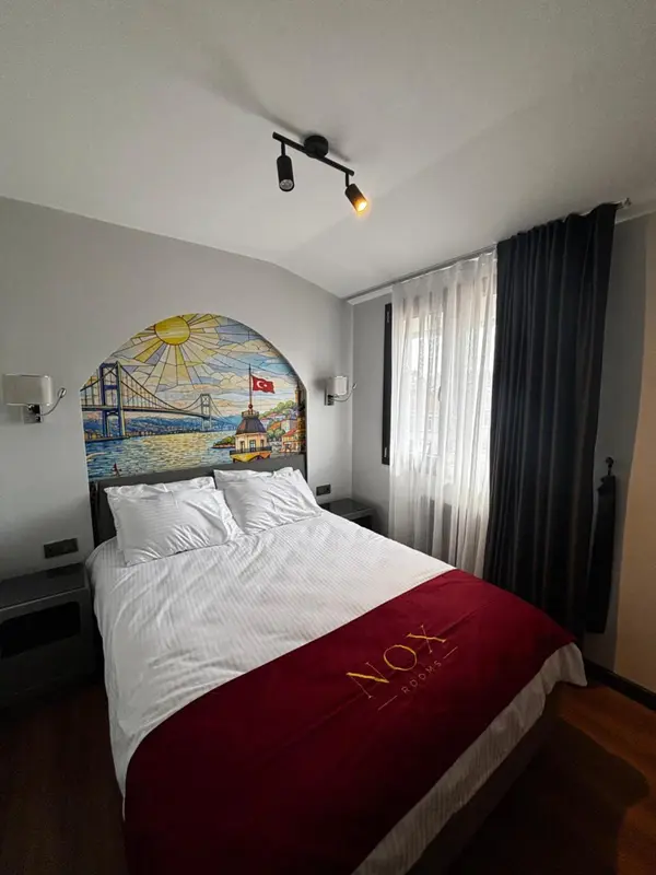 Une chambre avec un lit blanc et une décoration murale représentant un pont.