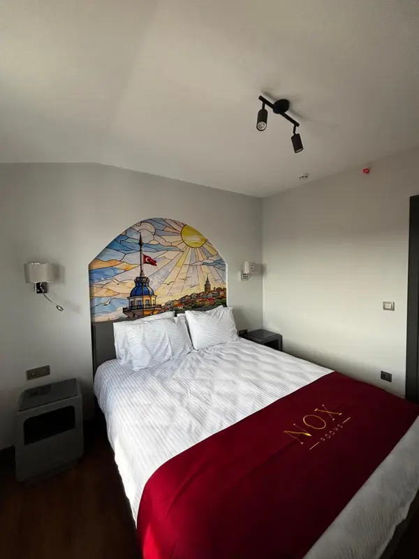 Une chambre avec un grand lit recouvert d'une courtepointe blanche et d'un plaid rouge.