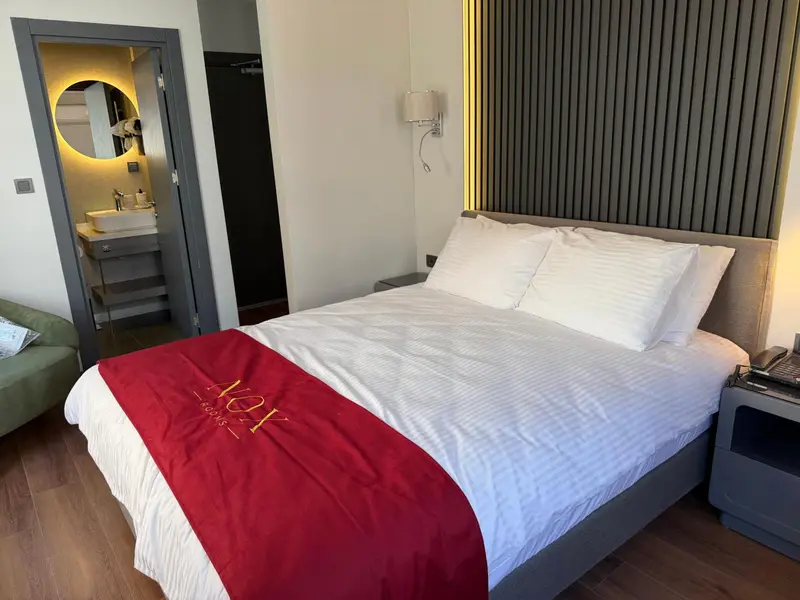 Une chambre d'hôtel moderne avec un grand lit recouvert d'une couverture rouge.