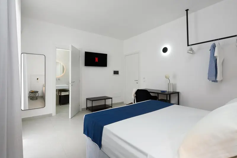 Une chambre lumineuse avec un lit fait et un miroir.