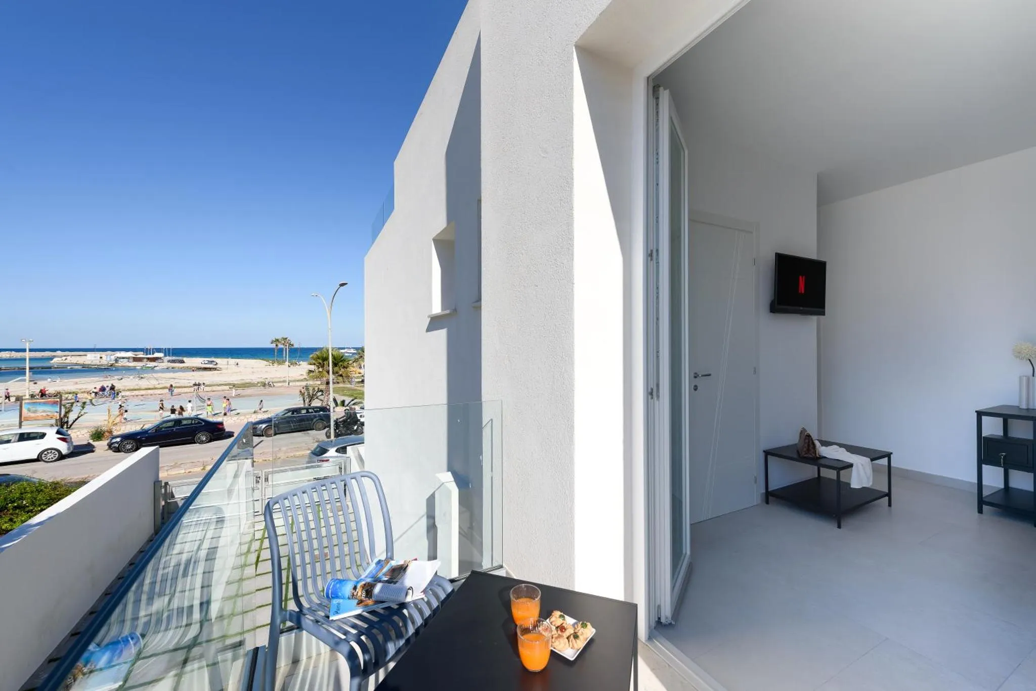 Une terrasse avec une table basse et des fauteuils offre une vue sur la mer et la plage.