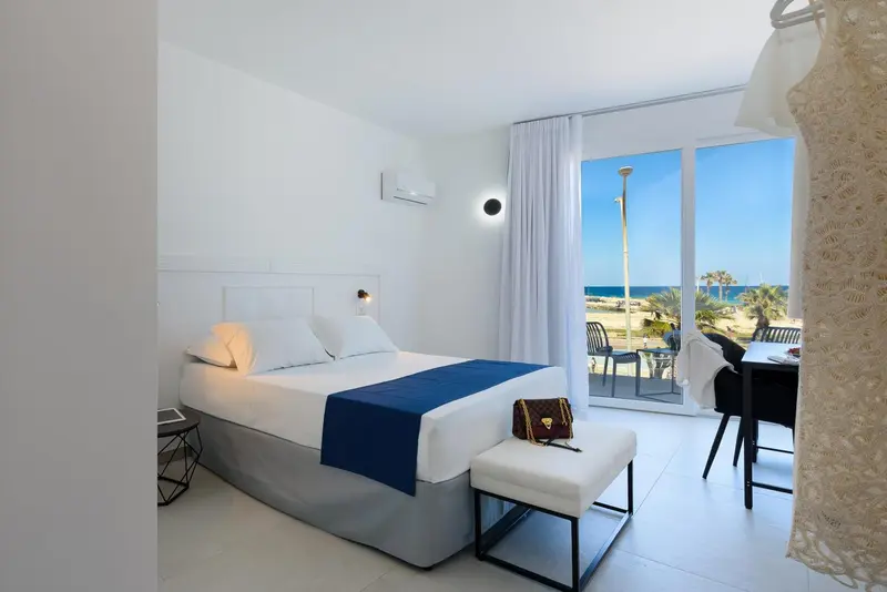 Chambre lumineuse avec un lit double et une vue sur la mer.