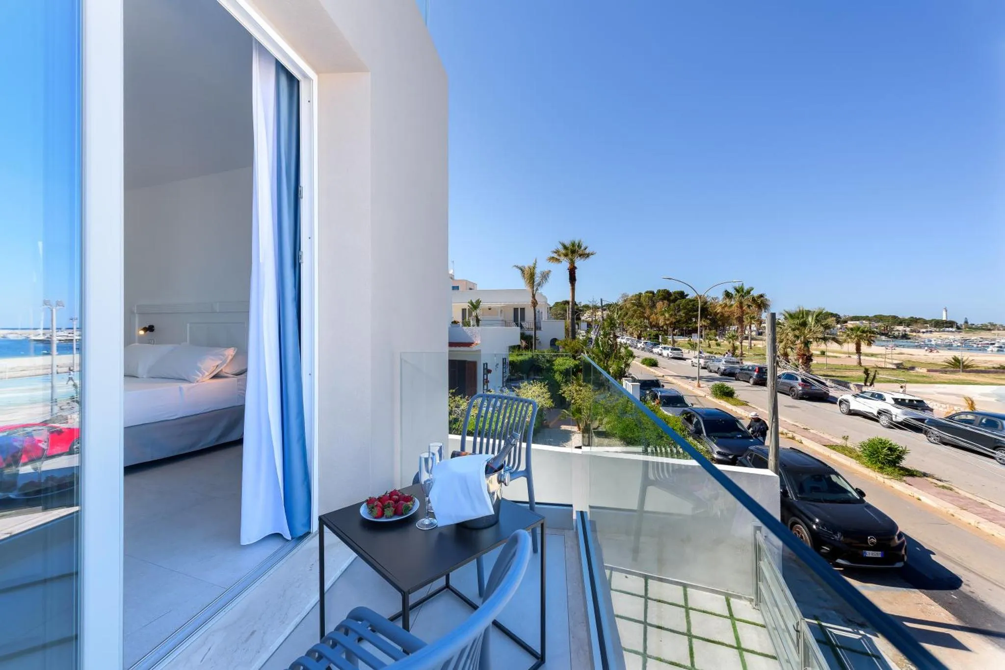 Une terrasse avec une table et des chaises offre une vue sur la mer et la végétation.