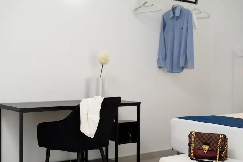 Une chemise bleue est suspendue à un cintre au-dessus d'un bureau noir.