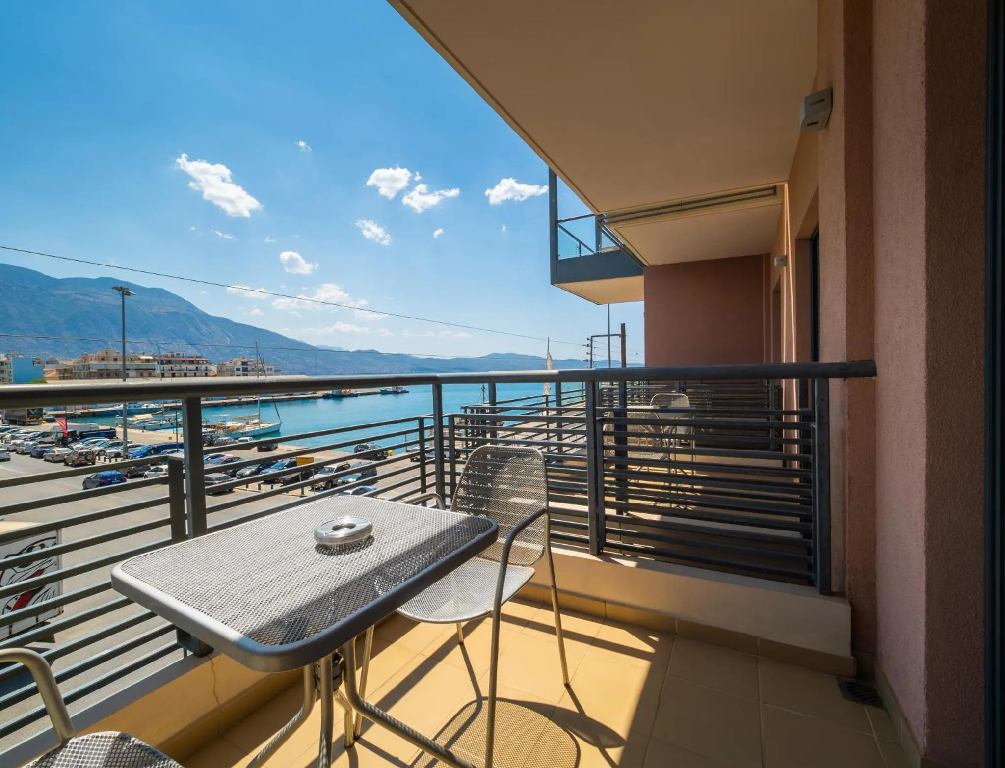 Une terrasse avec une table et des chaises offre une vue sur la mer et les montagnes.