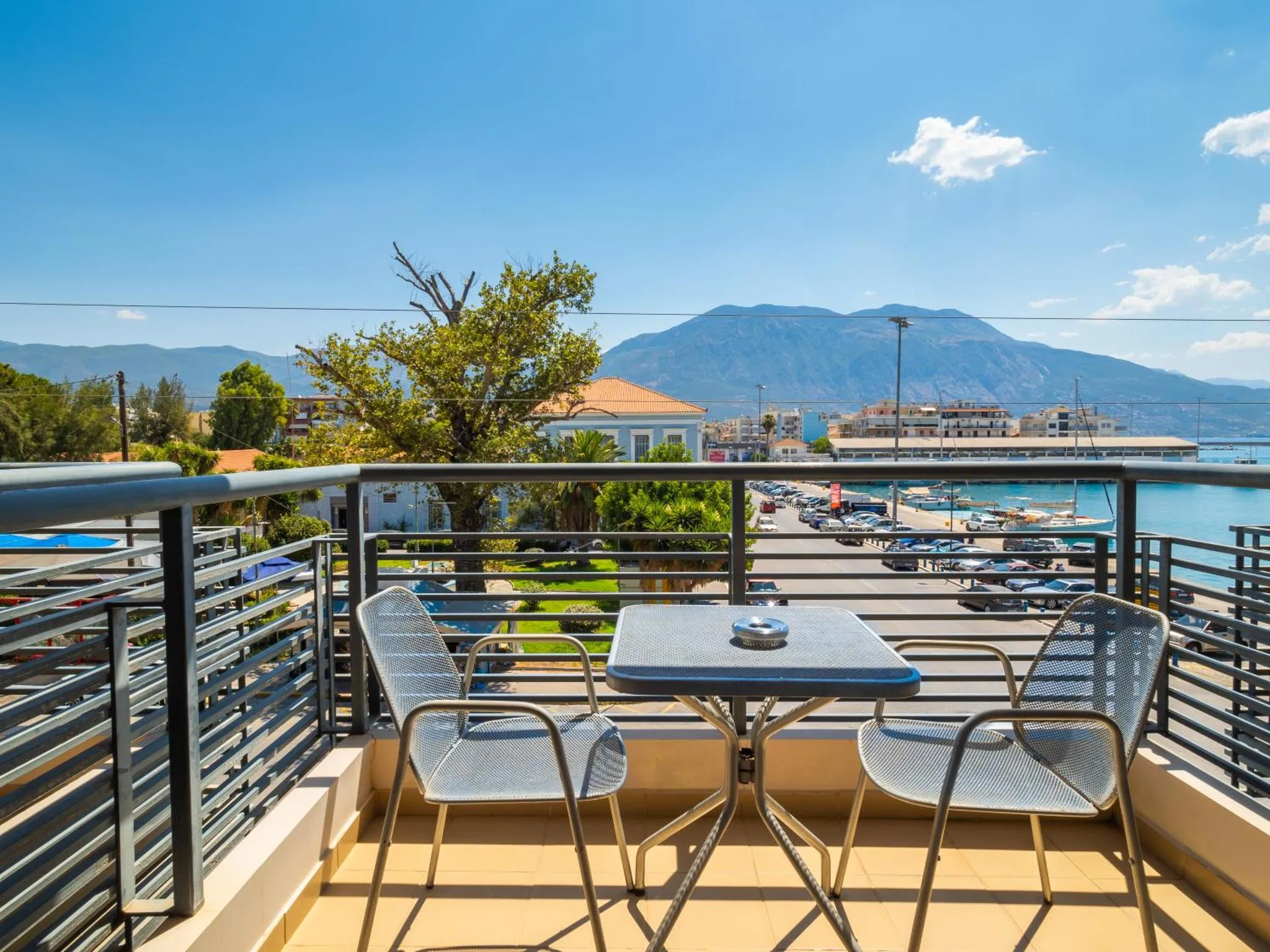 Terrasse avec table et chaises donnant sur la mer et les montagnes.