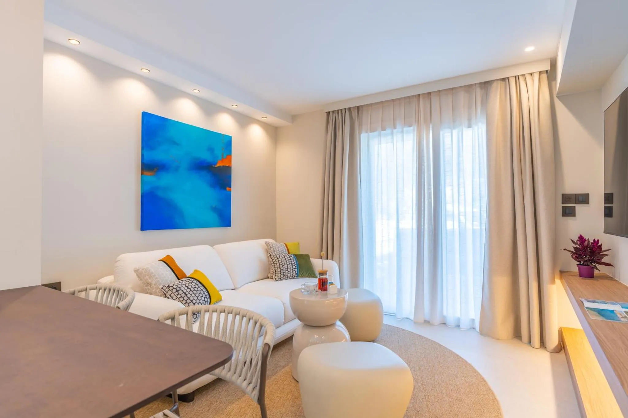 Espace de détente lumineux avec canapé blanc et rideaux clairs.