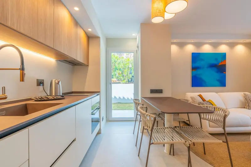 Une cuisine moderne s'ouvre sur un espace repas avec une table et des chaises.