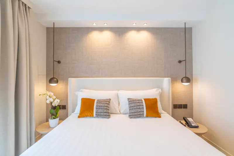 Un lit double avec une décoration florale et des coussins colorés dans une chambre lumineuse.