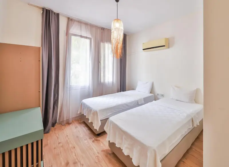 Une chambre lumineuse avec deux lits simples et une fenêtre.