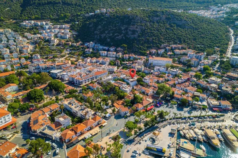 Vue aérienne d'une ville côtière avec des bâtiments aux toits rouges et une marina.