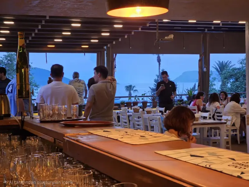 Un comptoir de bar en bois avec des verres et des bouteilles, devant une terrasse avec des tables et des personnes assises.
