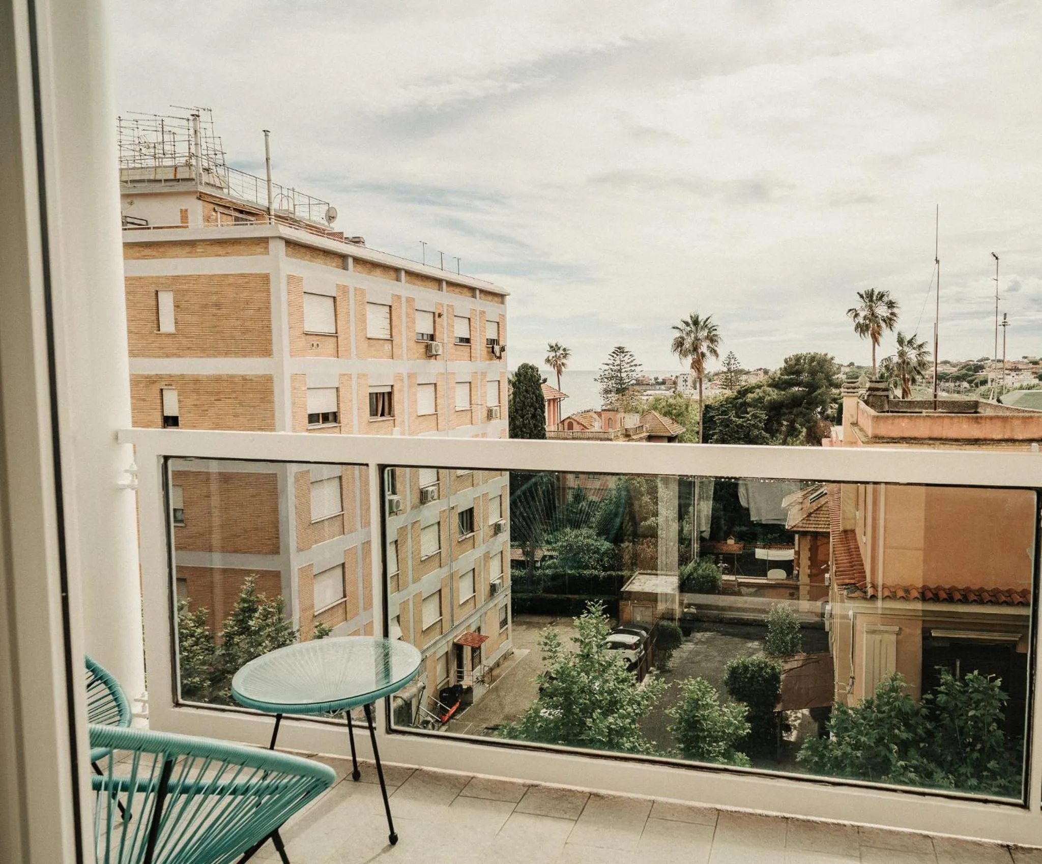 Une terrasse avec une table et des chaises offre une vue sur des bâtiments et la végétation.