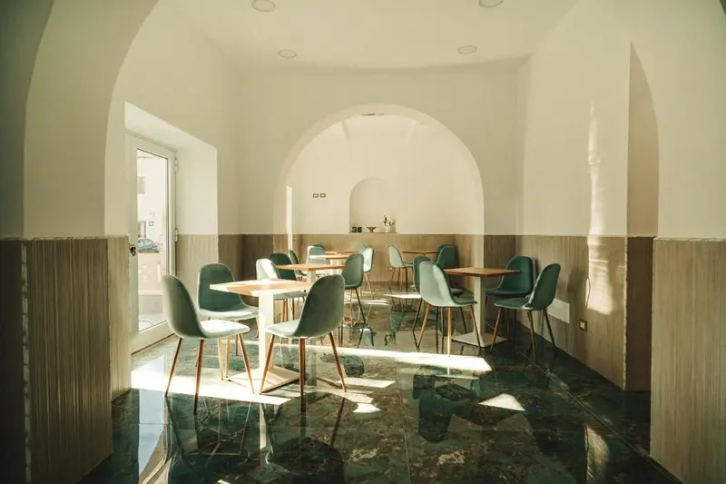 Une salle lumineuse avec des tables et des chaises vertes.