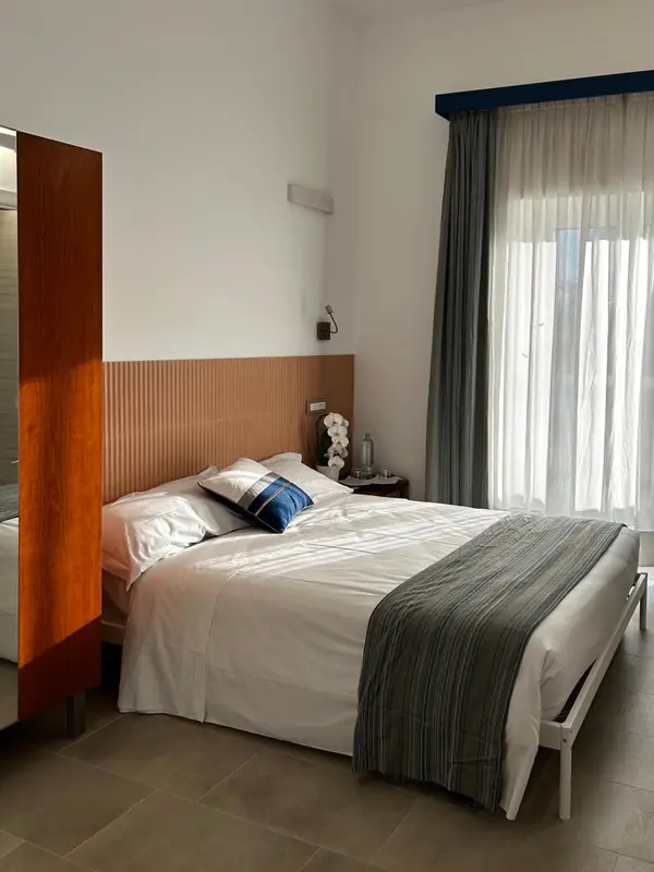 Une chambre lumineuse avec un grand lit recouvert d'une courtepointe.