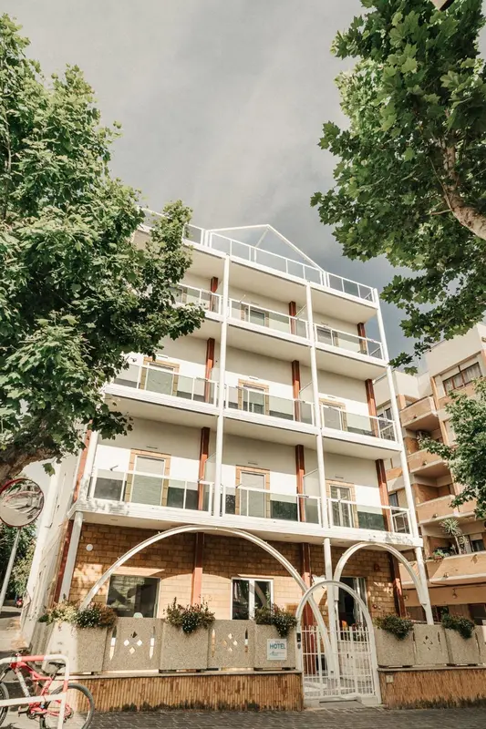 Bâtiment blanc à plusieurs étages avec des balcons fleuris.